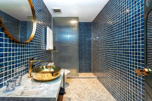 雅加達的住宿－Ashley Tugu Tani Menteng，浴室配有水槽和蓝色瓷砖墙壁。