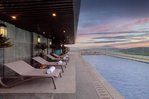 a row of lounge chairs next to a swimming pool at Altara Quy nhơn Residences Wins in Quy Nhon