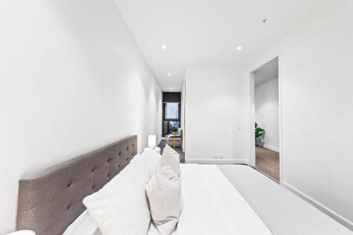 メルボルンにあるA Cozy & Lovely 2BR Apt Near Melbourne Centralの白い壁の客室で、ソファ(枕付)が備わります。