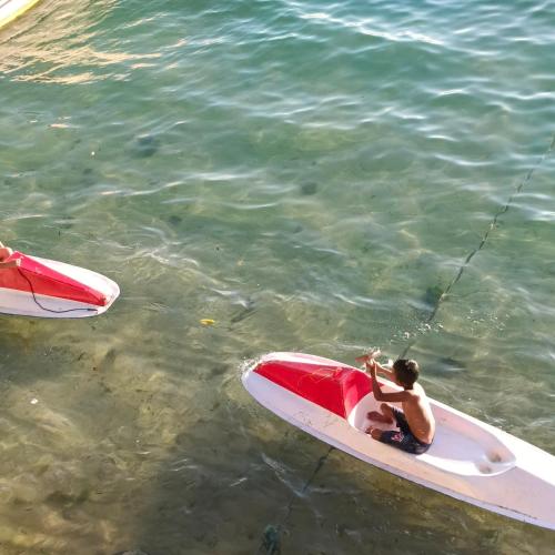 a man sitting on a surfboard in the water at Bunaken 18 Diving Resort and Cafe in Bunaken