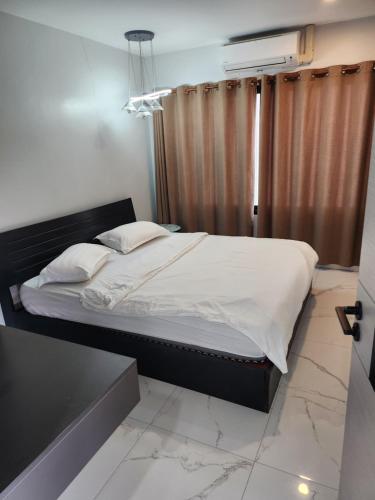 un letto con lenzuola e cuscini bianchi in una camera da letto di Pnd 아파트 a Vientiane