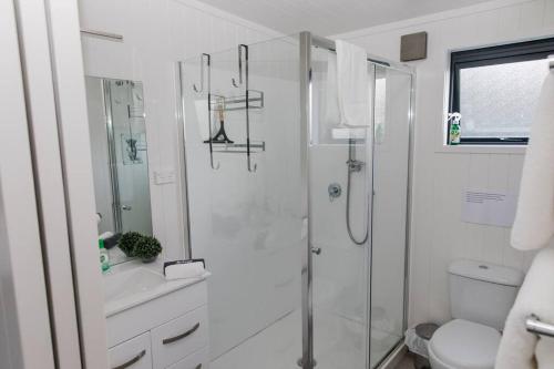 a white bathroom with a shower and a toilet at Bombay Hills Modern Retreat in Auckland