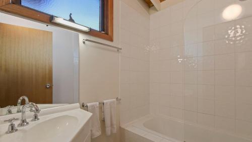 a bathroom with a tub and a sink and a bath tub at Fountains 6 in Mount Hotham