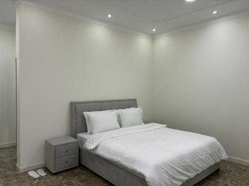 Dormitorio blanco con cama con sábanas y almohadas blancas en MFAPARTMENT, en Al Budayyiâ€˜