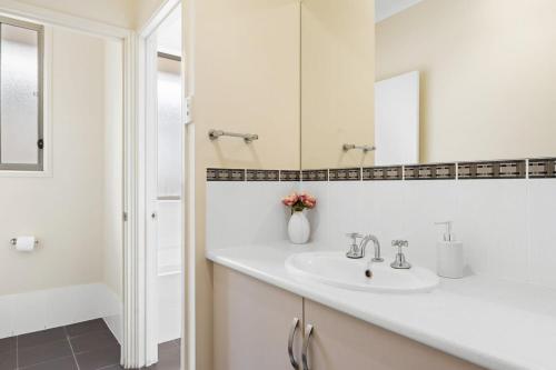 a white bathroom with a sink and a mirror at 3BR Home-City Fringe Location-Free WiFi & Parking in Keswick