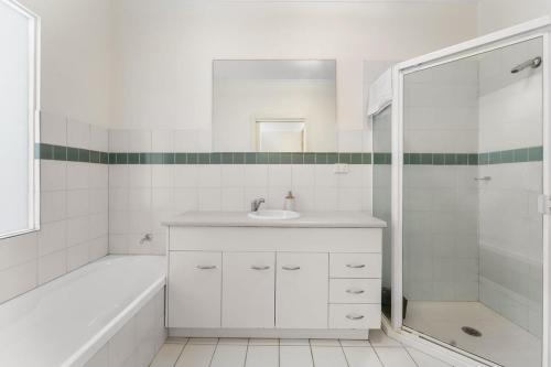 a white bathroom with a sink and a shower at Lego-Aerospace Free Parking CBD Chinatown in Adelaide