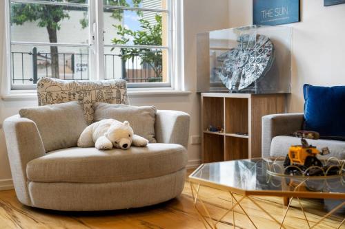 a stuffed teddy bear sitting on a chair in a living room at Lego-Aerospace Free Parking CBD Chinatown in Adelaide