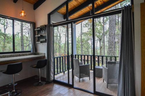 um quarto com uma varanda com cadeiras e janelas em Cabaña Mirtus em Mazamitla