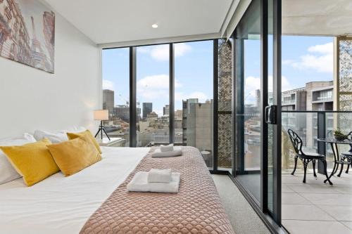 a bedroom with a bed with yellow pillows and a balcony at Heart of Adelaide Luxuy Apt Rundle Mall in Adelaide