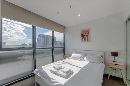 a bedroom with a white bed and a large window at Walk to Central Market Parking GYM&POOL City View in Adelaide