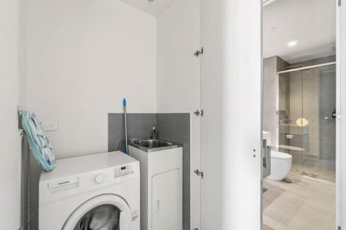 a white washing machine in a bathroom with a toilet at Taffy on Realm RundleMall Pool&Gym EasyLifestyle in Adelaide