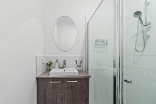 a bathroom with a sink and a shower with a mirror at New Luxury Stylish Elegant Townhouse for Families in Broadview