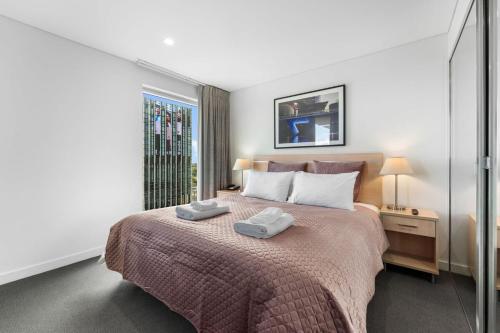 a bedroom with a bed with two towels on it at CBD Modern 2BR Free Parking in Adelaide