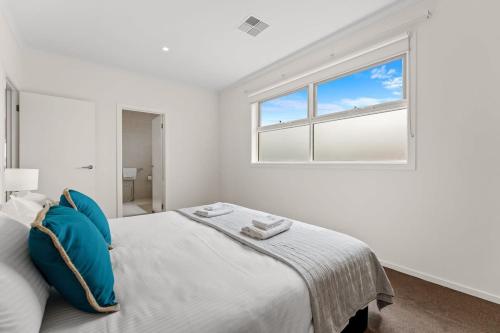 a white bedroom with a large bed with blue pillows at Amazing Lake View family-friendly Holiday Home in Cheltenham