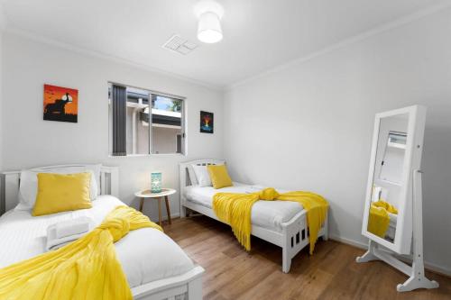 1 Schlafzimmer mit 2 Betten und gelber Bettwäsche in der Unterkunft Lovely Renovated 2BR Townhouse WiFi Parking in Sturt
