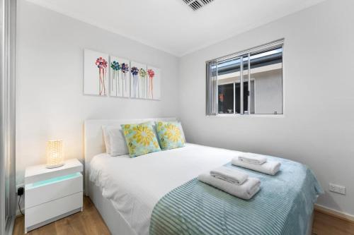 a white bedroom with a bed and a window at Lovely Renovated 2BR Townhouse WiFi Parking in Sturt