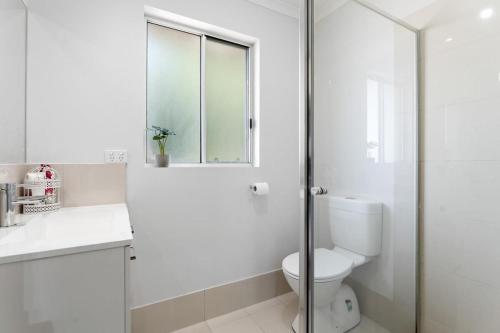 ein weißes Bad mit einem WC und einem Fenster in der Unterkunft Lovely Renovated 2BR Townhouse WiFi Parking in Sturt