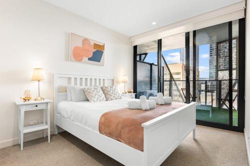 Habitación blanca con cama y balcón. en The 2BR City Escape - Stylish and Mordern en Adelaida