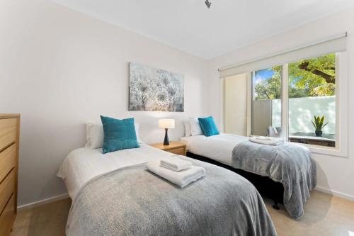 two beds in a room with a window at Family friendly CBD 3BR Apt Hurtle Square in Adelaide
