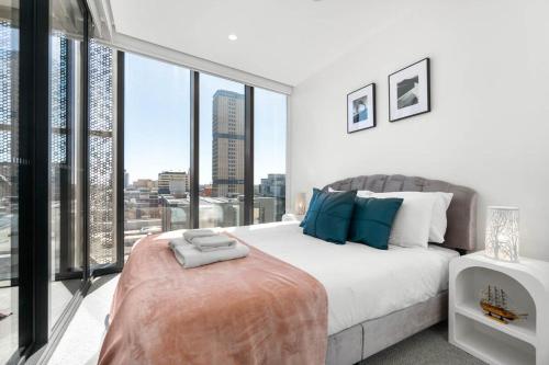 a bedroom with a large bed and large windows at The amazing 1BR CBD Apt Premium Location in Adelaide