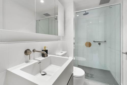 a white bathroom with a sink and a shower at The amazing 1BR CBD Apt Premium Location in Adelaide