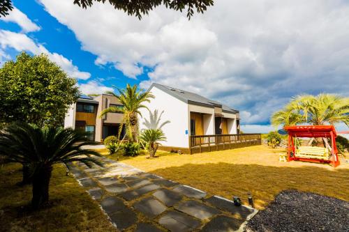 a house with a red structure in front of it at Jeju batdol guesthouse in Jeju