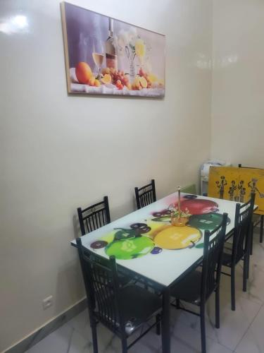 a dining room table with chairs and a painting on the wall at Appartement meublé in Dakar