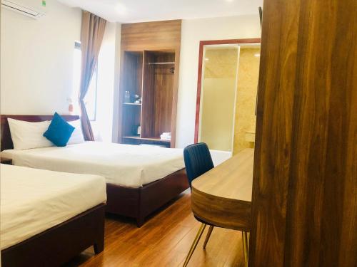 a hotel room with two beds and a chair at Le Centre Pleiku Hotel in Pleiku