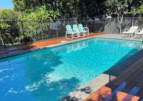 a swimming pool with two chairs and a group at The Sundowner, 25 Lentara St - luxury pet friendly retreat with pool in Fingal Bay