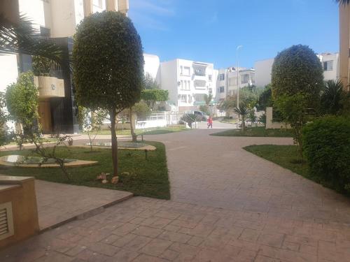a walkway in a city with trees and buildings at Appartement 141m2 Moderne Haut Standing de 3 Chambres - Internet Fibre à Ennasr 2 - Idéal pour Famille - Service Navette in Burj at Turkī