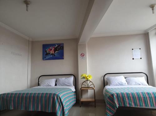 1 dormitorio con 2 camas y una foto en la pared en Hospedaje Fenix, en Cuenca