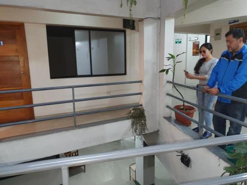 dos personas de pie en las escaleras de un edificio en Hospedaje Fenix, en Cuenca