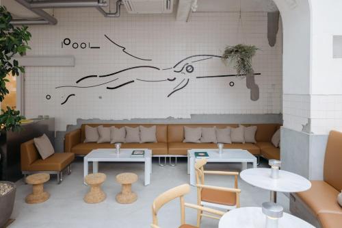 a coffee shop with tables and couches in a room at KIRO Hiroshima by THE SHARE HOTELS in Hiroshima