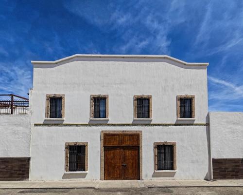 a white building with a wooden door and windows at POSADA GUADALUPE AGUASCALIENTES in Aguascalientes
