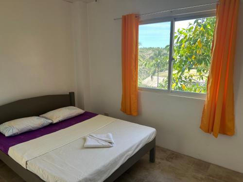 1 dormitorio con 1 cama y una ventana con cortinas de color naranja en Annabel's Resort, en Ferrol