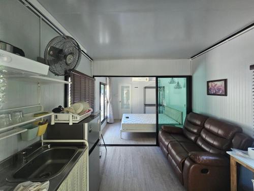 uma cozinha e uma sala de estar com um sofá num quarto em Srithanu Haus em Haad Chao Phao