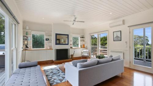 a living room with a couch and a tv at The White Cottage - Relaxed Metung Getaway in Metung