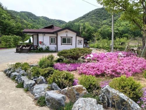 a house with a garden with flowers and rocks at Sangjoo munjangdae healing house in Sangju