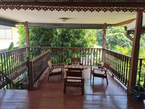 une terrasse couverte en bois avec des chaises et une table. dans l'établissement Lamour Guesthouse ละเมอ เกสต์เฮาส์, à Pattaya (nord)