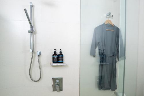 een badkamer met een douche en een badjas aan de muur bij The Straits Melaka by Perfect Host in Melaka