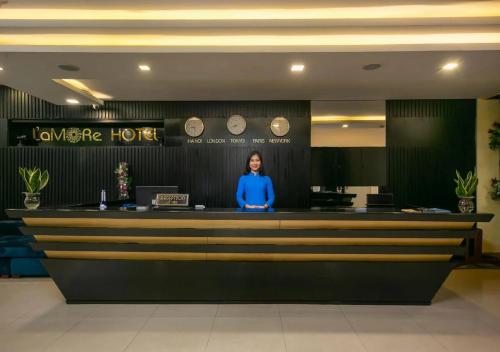 a woman standing at the counter of a hotel at L'emore Hotel Da Nang in Da Nang