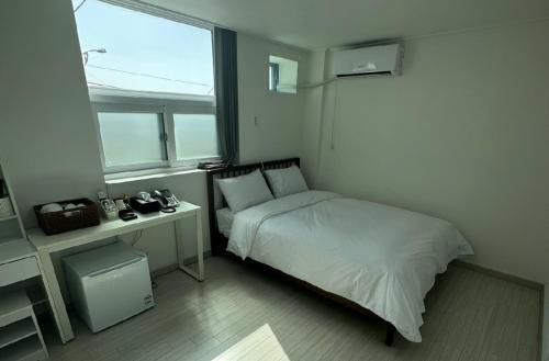 a bedroom with a bed and a desk and a window at Goseong geojinhotel pension in Goseong