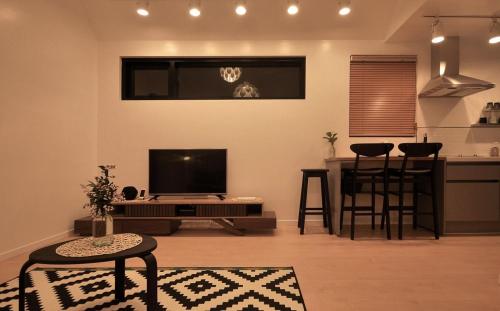 a living room with a flat screen tv and a kitchen at Ilo Pension in Seogwipo