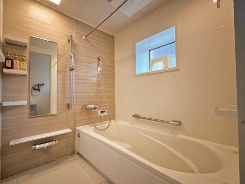 a bathroom with a tub and a shower and a window at ヴィラ山間堂 Terrace Villa BBQ Bonfire Fuji view Annovillas in Fujikawaguchiko