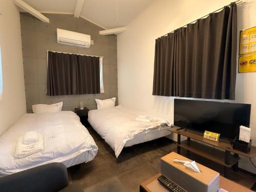 Cette chambre comprend 2 lits et une télévision à écran plat. dans l'établissement Necoana Glamping富士山景BBQトレーラーヴィラ, à Fujikawaguchiko