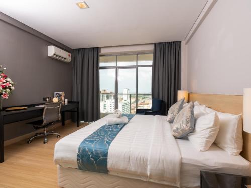 a bedroom with a bed with a desk and a window at The Straits Melaka by Perfect Host in Melaka