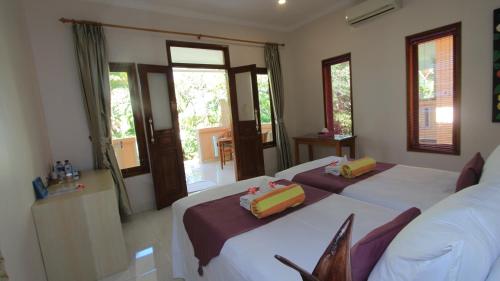 a bedroom with two beds and two windows at Poinciana Resort in Tejakula