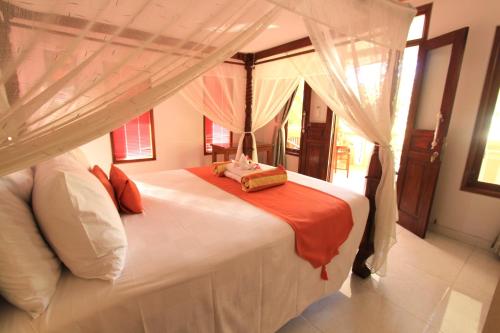 a bedroom with a large white bed with a canopy at Poinciana Resort in Tejakula