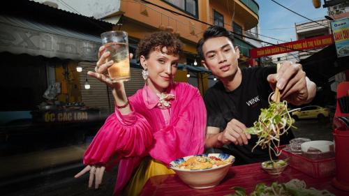 Ein Mann und eine Frau essen mit einem Drink. in der Unterkunft Wink Hotel Danang Centre - 24hrs stay in Đà Nẵng