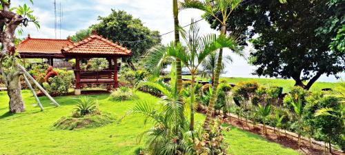 a garden with a gazebo in a field at JOGLO APONG Beachfront Apartment in Tegallengah